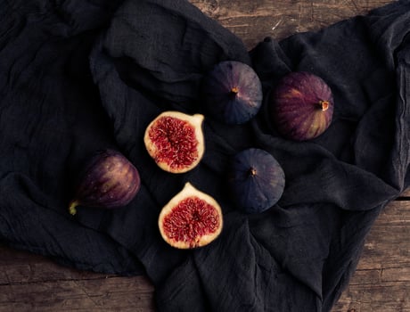 ripe whole and halved purple figs on a black napkin photo