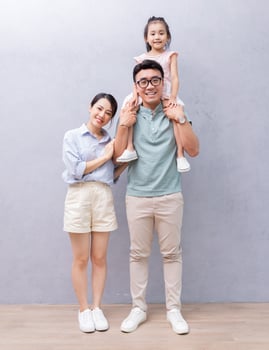 Young Asian family standing on background photo