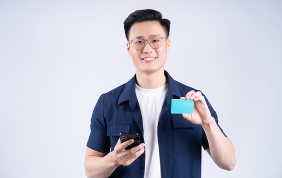 Image of young Asian man holding bank card on white background photo