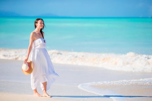 Young beautiful woman on white sand tropical beach. Caucasian girl with hat background the sea photo