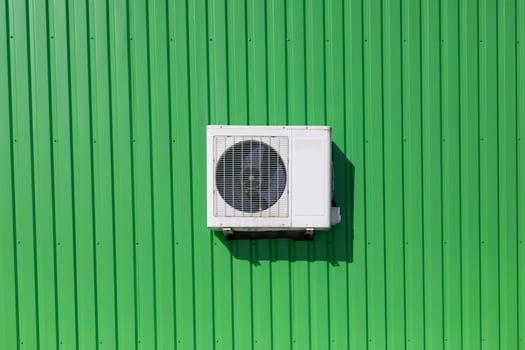Air conditioning on wall. Cooling equipment. Green wall of industrial building. photo