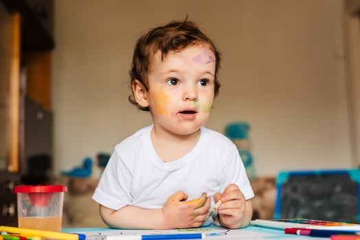 a small cute boy paints with brushes and colored paints on a sheet of paper photo