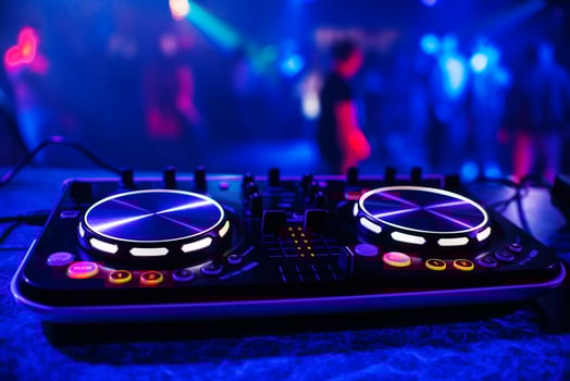 DJ console for mixing music with blurry people dancing at a nightclub party photo