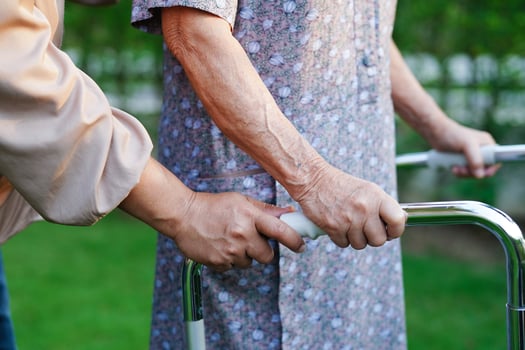 Caregiver help Asian elderly woman disability patient walk with walker in park, medical concept. photo