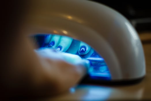 Closeup of the hand of a woman inside a uv lamp curing her recently applied gel nail polish photo