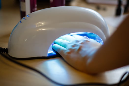 Closeup of the hand of a woman inside a uv lamp curing her recently applied gel nail polish photo