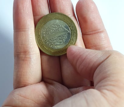 Turkey in June 2022. Isolated white photo of a hand holding a Turkish one lira coin.