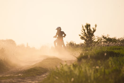 photo of a motorcyclist at sunset riding speed along the road