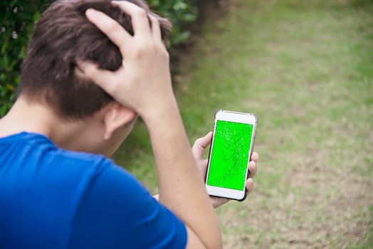 Man seriously looking at mobile phone with broken cracked screen display need to be fixed, mobile repair shop concept photo