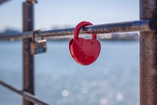 A heart-shaped door lock, a symbol of love and fidelity with a lake in the background, hangs on the fence of the bridge. The heart-shaped castle symbolizes loyalty and love photo