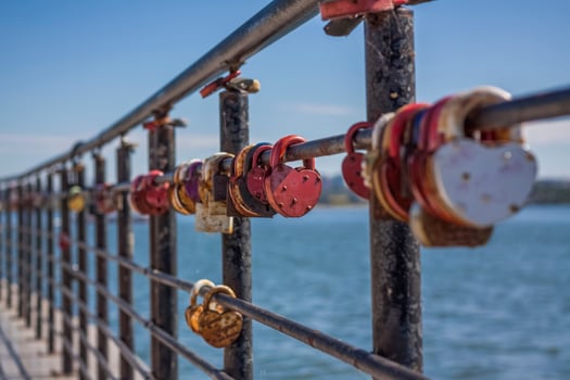 A heart-shaped door lock, a symbol of love and fidelity with a lake in the background, hangs on the fence of the bridge. The heart-shaped castle symbolizes loyalty and love photo