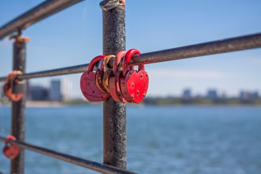 A heart-shaped door lock, a symbol of love and fidelity with a lake in the background, hangs on the fence of the bridge. The heart-shaped castle symbolizes loyalty and love photo