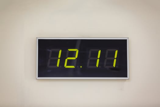 Black digital clock on a white background showing time twelve hours eleven minutes photo