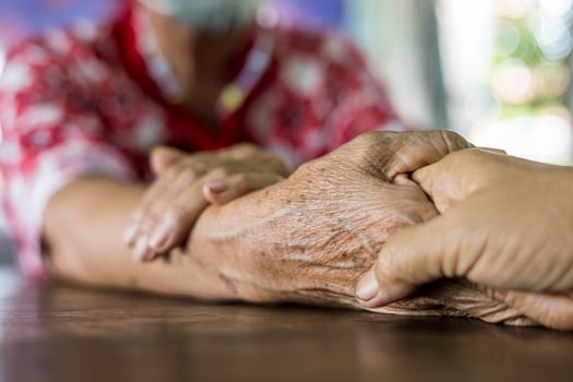 Close up hands of two elderly Thai women sitting and holding hands together. photo