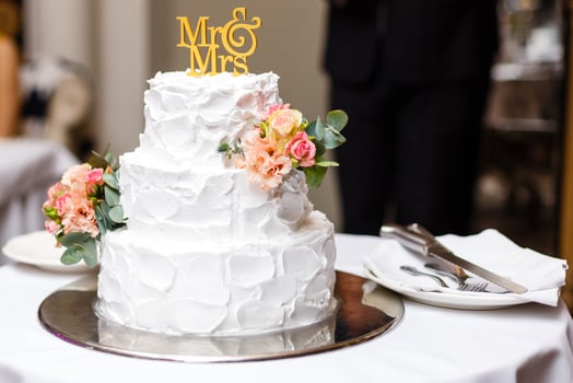 a multi level white wedding cake on a silver base and pink flowers on top photo