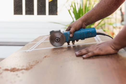 Hands of carpenter cutting piece of wood with electric circular saw. photo