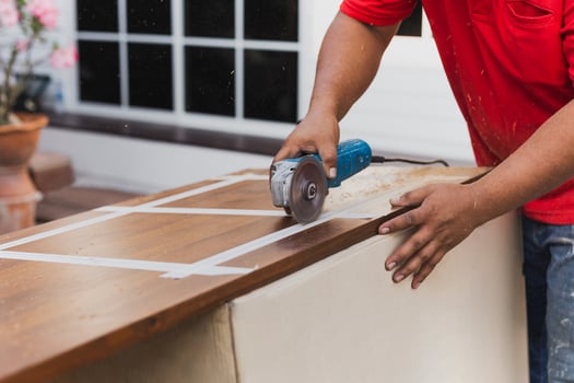 Hands of carpenter cutting piece of wood with electric circular saw. photo