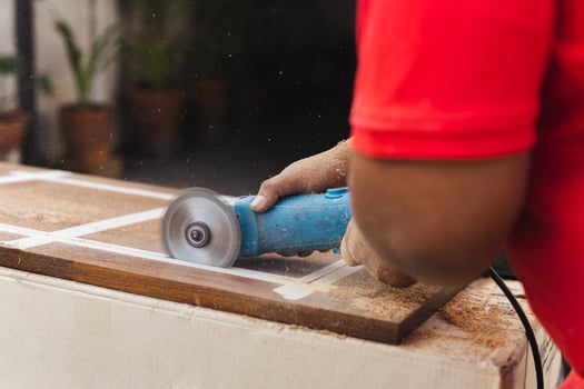 Hands of carpenter cutting piece of wood with electric circular saw. photo