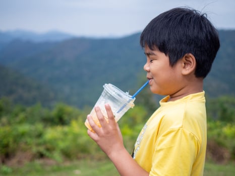 boy sucking a drink from a glass with a valley background photo