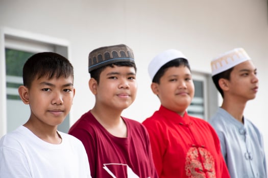 Portrait asian muslim or islamic boys sitting with muslim boys in a row to pray or to do the religious activity, soft and selective focus. photo