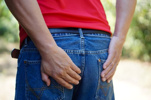 Closeup man wears jeans, use his hands to touch bottom, feel hurt.  Concept , getting hemorrhoids, diarrhea, pain in bottom from long sitting, health problem, healthcare. photo