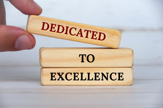 Dedicated to excellence text on wooden blocks with wooden cover background. Business motivation concept photo