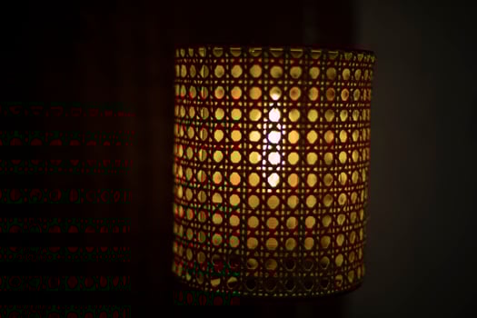 Lamp in dark. Wooden lampshade around incandescent lamp. photo