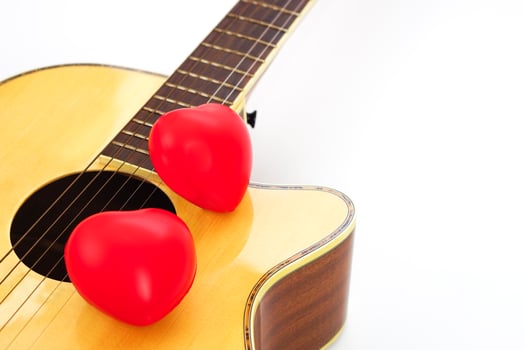 Acoustic guitar and red heart on a white background. Love and music concept. photo