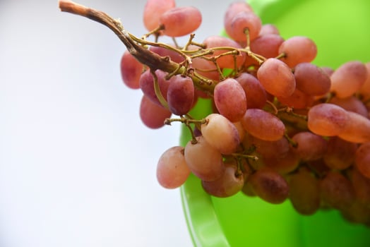 A branch of red grapes on a green plate. Washed grapes in a plastic container. photo