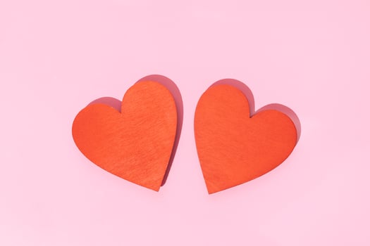 Two Wooden red heart shape isolated on pink background photo