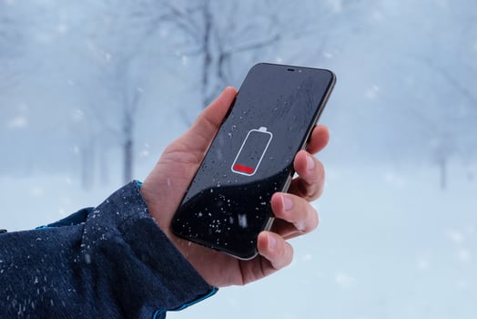 Low battery on smartphone in man hand. Winter, cold time.  Concept of faster battery discharge at low temperatures photo