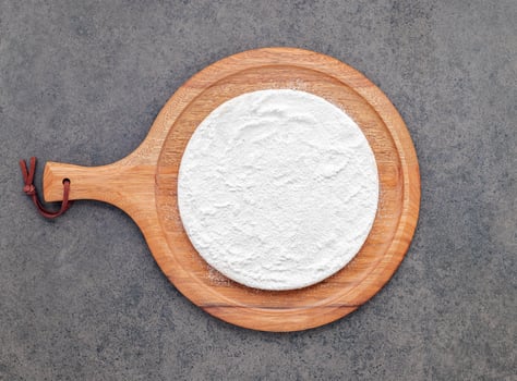 Pizza dough in wooden pizza platter set up on dark concrete. Pizza tray on dark concrete background flat lay and copy space. photo