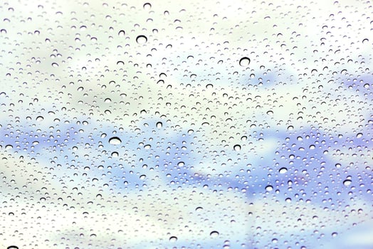 Closeup and crop rain drop on glass and blurry light blue background photo
