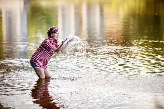 beautiful young girl in a plaid shirt and short denim shorts in pin-up style stays in water of river photo