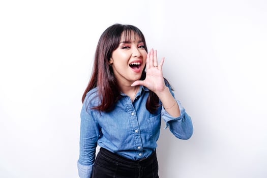Young beautiful woman wearing a blue shirt shouting and screaming loud with a hand on her mouth. communication concept. photo