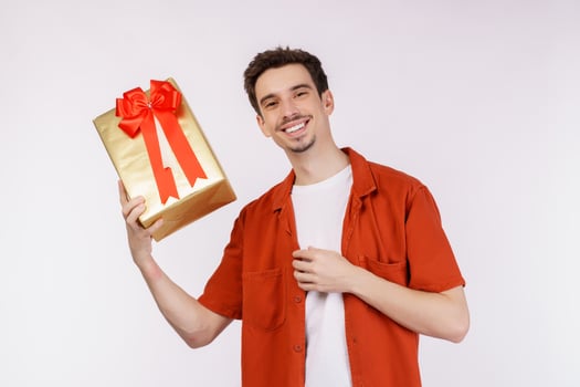 Portrait of Happy young caucasian man showing present box and looking at camera isolated over white background photo