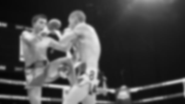 Blurred images black and white photo style of Thai boxing or Muay Thai or Kickboxing which local and foriegn boxer are fighting on the ring at indoor stage as martial art sport. Muay Thai Kick boxing