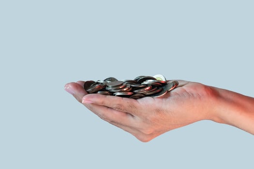 a pile of coins in people's hand isolated on blue background. money-savings concept. photo