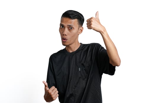 asian man wearing black training t-shirt, feeling happy and giving thumbs up. Isolated by white background photo