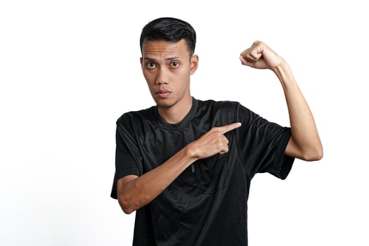 asian man wearing black training t-shirt, showing a strong stance with raised arms and muscles. Isolated by white background photo
