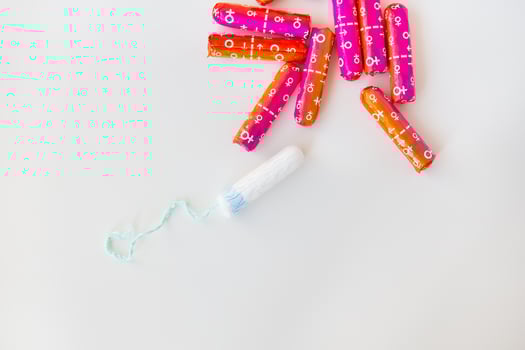 Medical female tampon in pink and orange packaging on a white background. Hygienic white tampon for women. Cotton swab. Menstruation, contraception. photo