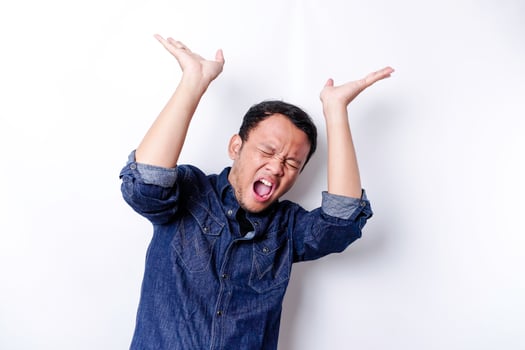 Shocked Asian man wearing blue shirt pointing at the copy space on top of him, isolated by white background photo