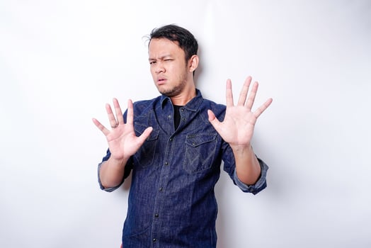 Handsome Asian man wearing blue shirt with hand gesture pose of stop or prohibition with copy space photo