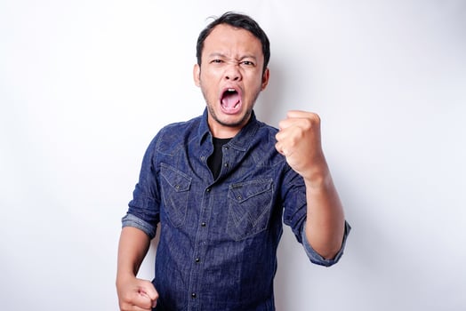 The angry and mad face of Asian man in blue shirt isolated white background. photo