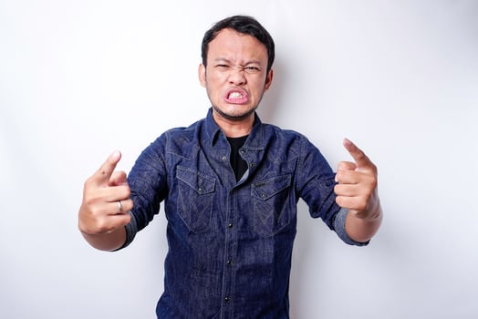The angry and mad face of Asian man in blue shirt isolated white background. photo