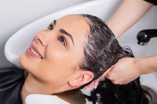 professional hairdresser washing hair of young woman in beauty salon photo