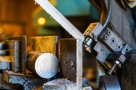 A metal band saw in the workshop cuts a metal rod with a liquid refrigerant. Gear blade of the machine photo