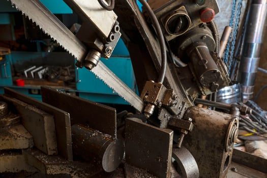 A metal band saw in the workshop cuts a metal rod with a liquid refrigerant. Gear blade of the machine photo