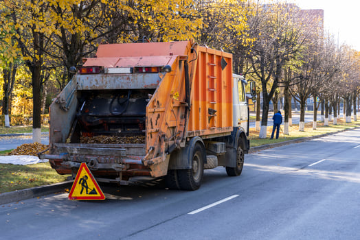 Garbage truck removes autumn fallen leaves, disposal of fallen autumn leaves by employees of public utilities photo