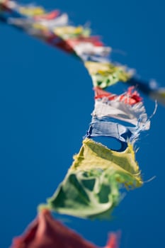 Colorful Tibetan Buddhist prayer flags waving in the wind on blu photo